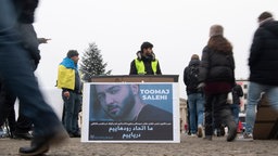 Protestplakat mit einem Bild von Toomaj Salehi auf dem Pariser Platz in Berlin. © picture alliance/dpa Foto: Paul Zinken
