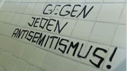 Der Spruch "Gegen jeden Antisemitismus!" prangt an einer Toilettenwand der Philipps Universität in Marburg. © dpa Foto: Arne Dedert
