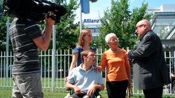 Christoph Lütgert mit Versicherungsopfern vor einem Gebäude der Allianz. © NDR