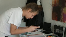 Die Hamburger Schülerin Jana fotografiert ihre handgeschriebenen Arbeiten mit dem Handy um sie an ihre Lehrerin zu schicken. © NDR/ARD 