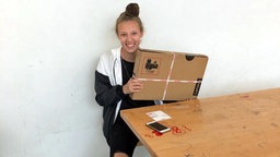 Die Hamburger Schülerin Jana hält einen im Paket befindlichen Laptop in den Händen. © NDR/ARD 