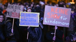 Protestierende halten beim Rammstein-Tourauftakt in Leipzig Schilder gegen Sänger Till Lindemann und für Solidarität mit Opfern sexualisierter Gewalt hoch. © picture alliance/dpa Foto: Hendrik Schmidt
