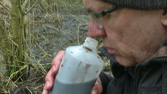 Ein Mann riecht an einer Wasserprobe  