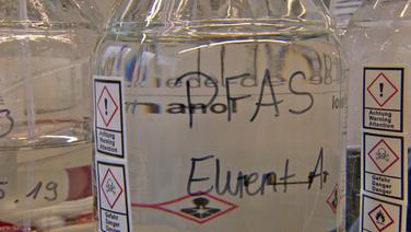 Ein Glasgefäs mit einer Flüssigkeit, die per- und polyfluorierte Alkylsubstanzen (PFAS) enthält. © NDR 