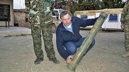Jan van Aken (Die Linke) mit einer"MILAN"-Panzerabwehrrakete in Syrien. © NDR/ARD 