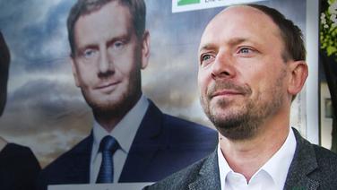 Marco Wanderwitz steht neben einem Plakat von Sachsens Ministerpräsident Michael Kretschmer. © NDR/ARD Foto: Screenshot