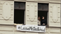 Rixa und Caro sitzen am Fenster. Ein Banner mit der Aufschrift "Leave noone behind" ist zu sehen ©  Ingo Mende Foto:  Ingo Mende